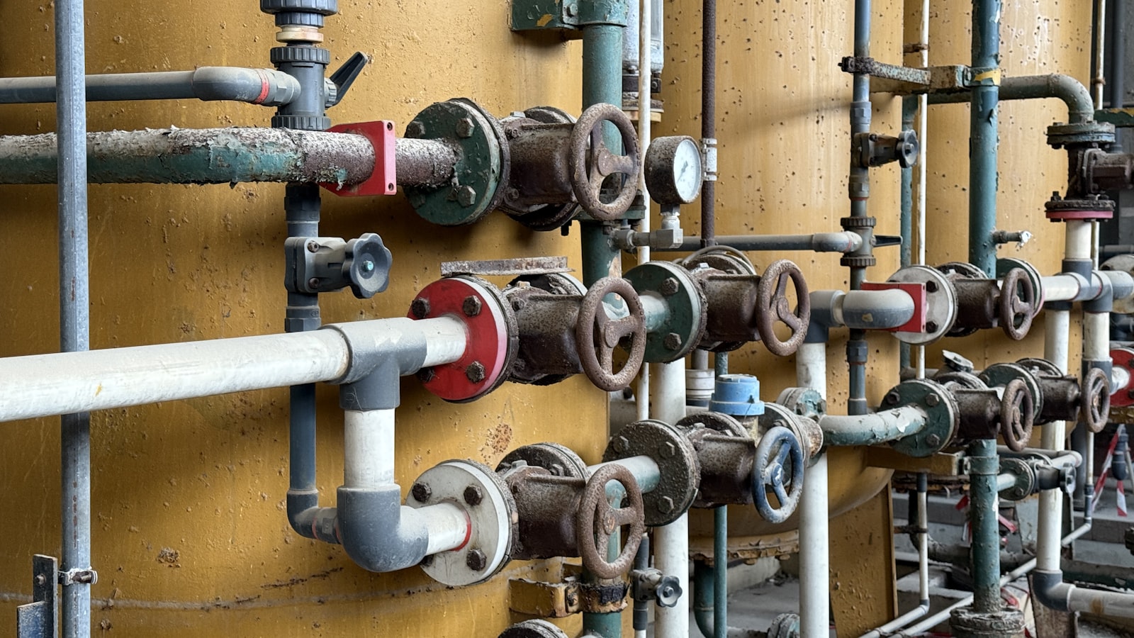 Commercial pipe manifold, valves, and tanks in a mechanical room.